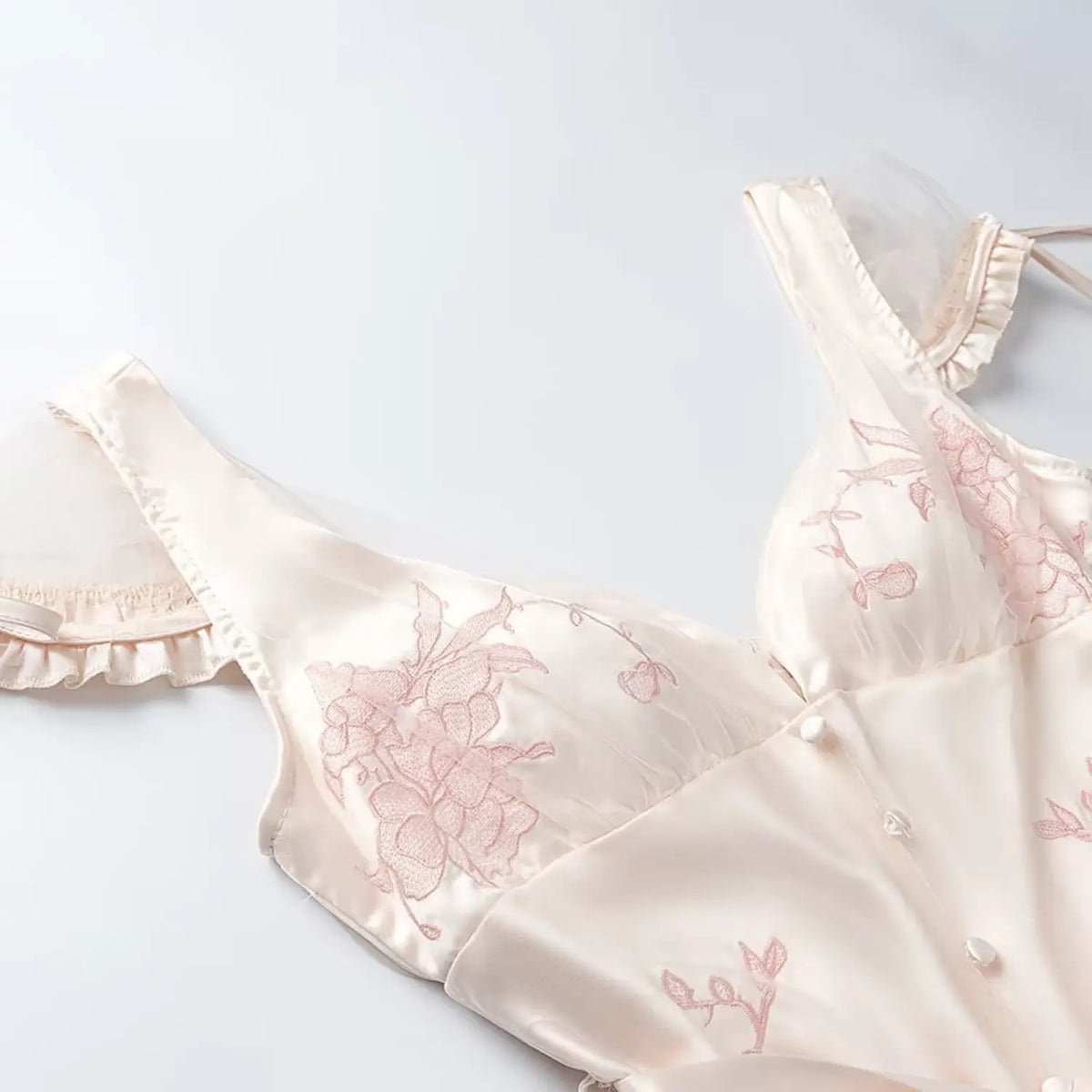 Close up of pink floral embroidery on cream satin midi dress bust, v-neck and mesh sleeve detail