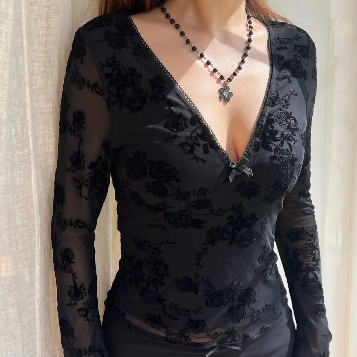 Model wearing floral flocked v neck bow mesh long sleeve top, side angle view