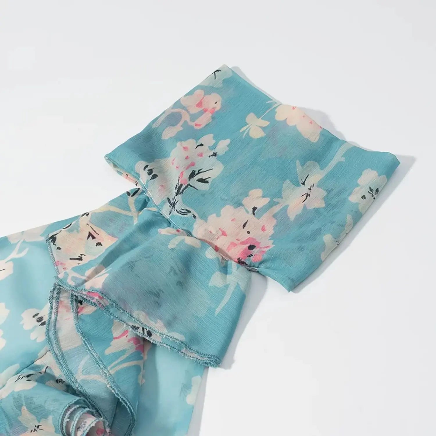 Close‑up detail of ruffled halter neck, blue floral crinkle chiffon fabric with watercolor flower print