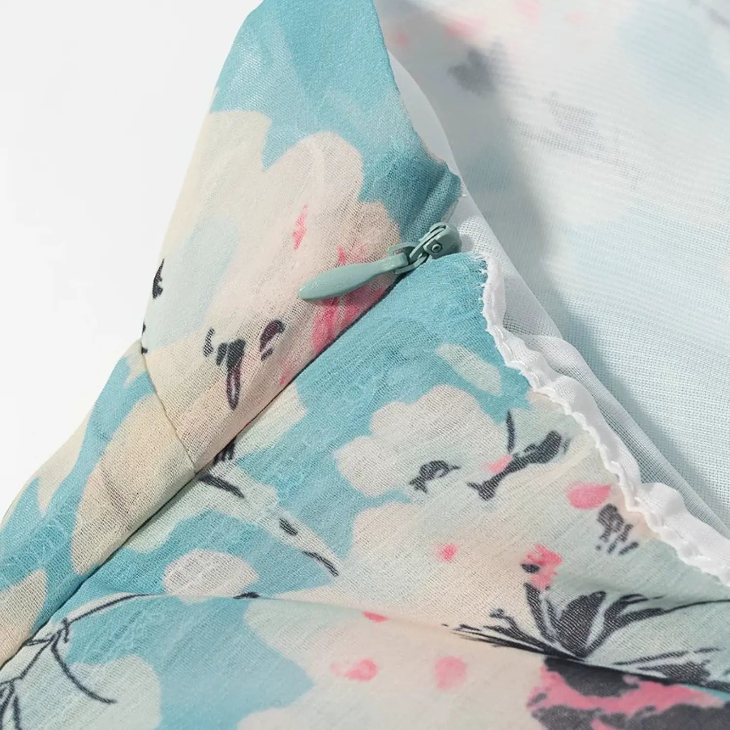 Macro close‑up of light blue invisible side zipper on blue floral chiffon halter dress