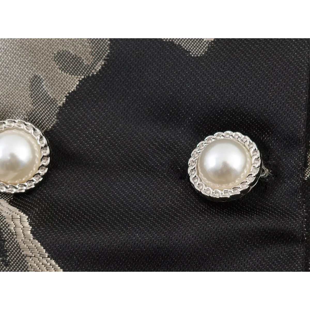 Macro shot of decorative pearl buttons with silver twisted rim on black grey floral jacquard blazer mini dress