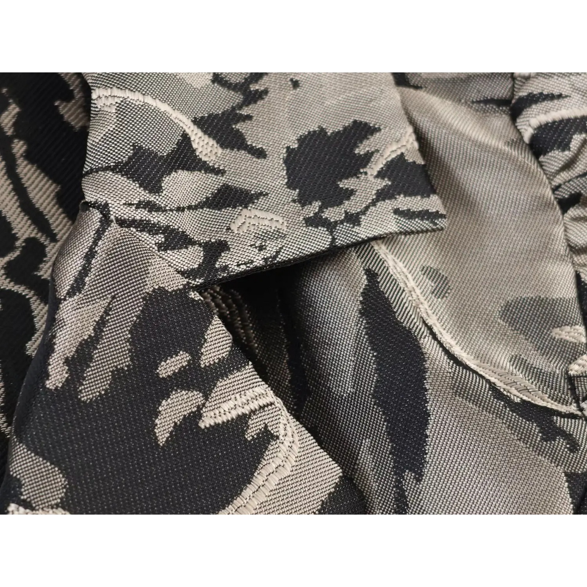 Extreme close-up of woven jacquard fabric texture, black and grey abstract floral pattern on mini dress