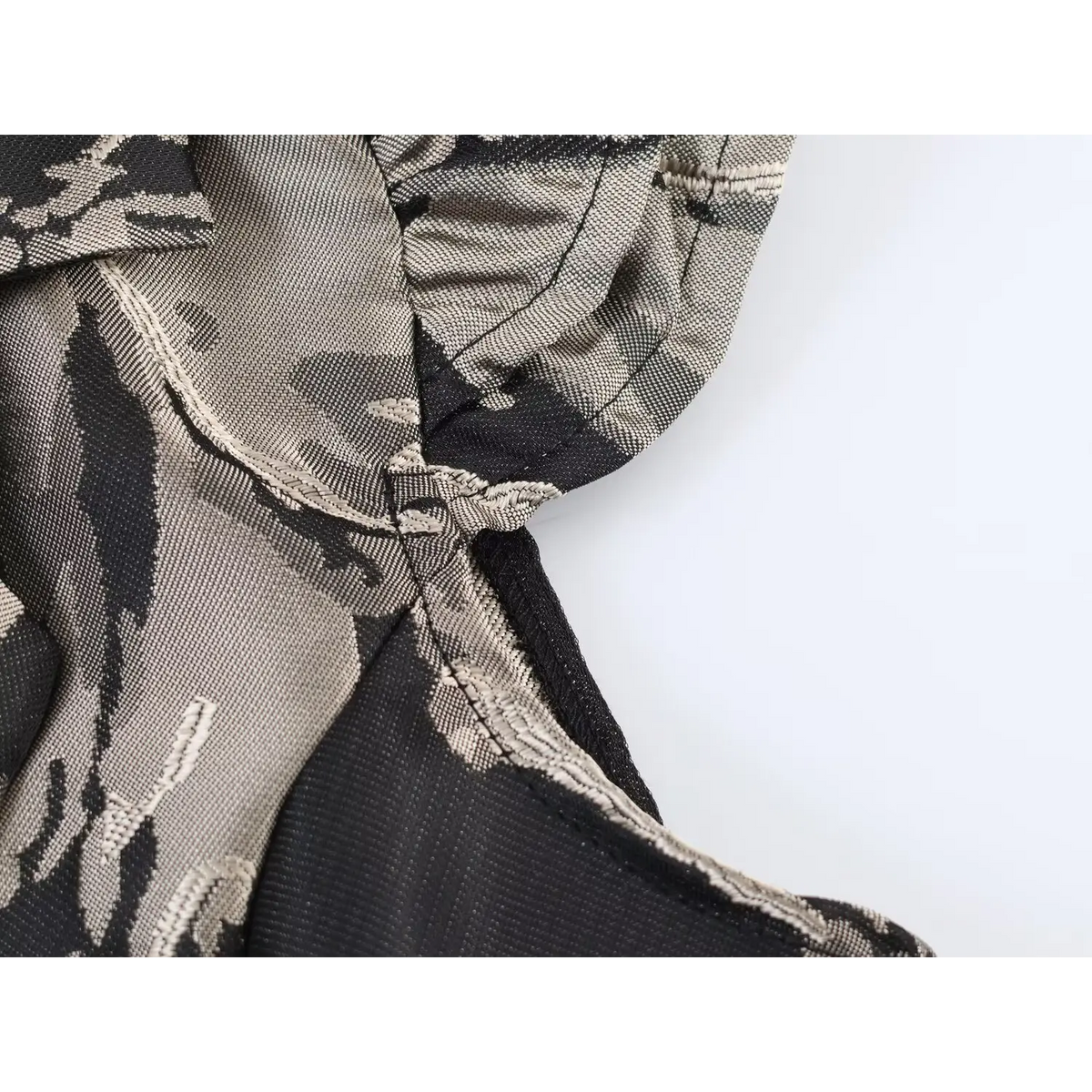 Close-up of stitching seam and ruffle cap sleeve on black grey floral jacquard mini dress, textured woven fabric detail