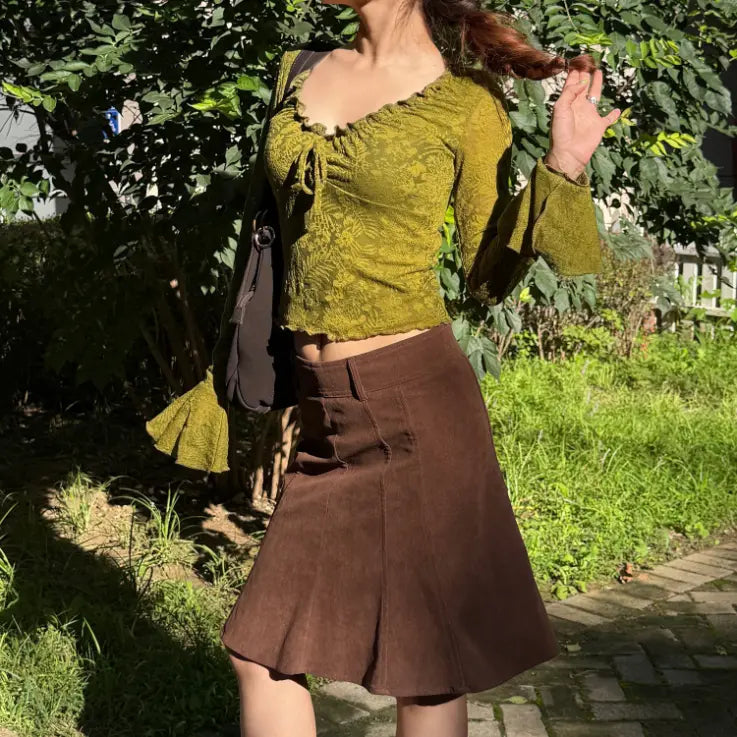 Model wearing olive floral jacquard ruffle tie neck bell sleeve crop top with brown skirt, outdoor full view