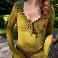 Model wearing olive floral jacquard ruffle tie neck bell sleeve crop top, outdoor view