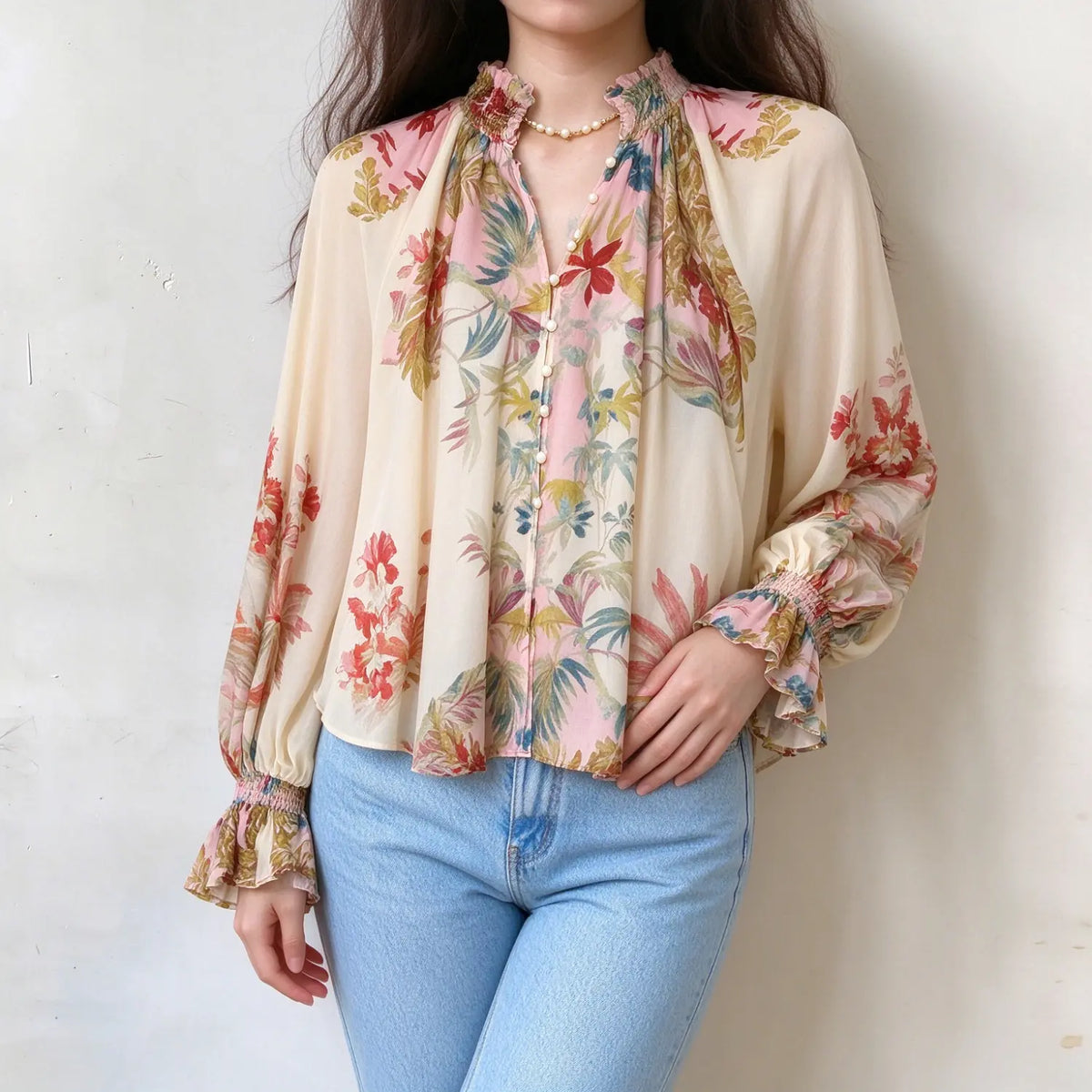 Female model wears cream base floral print blouse, ruffle smocked high neck, v-neck placket with pearl buttons, balloon long sleeves with ruffle cuffs, front torso shot