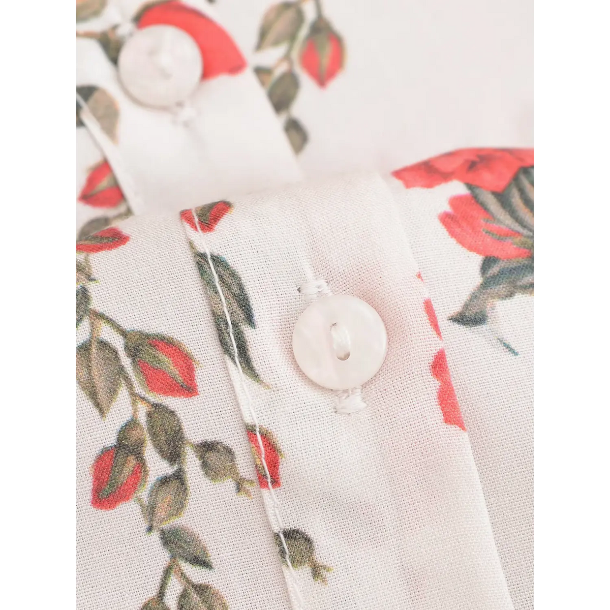 Macro shot of white shell button on floral maxi dress, showing stitching and red flower print woven fabric