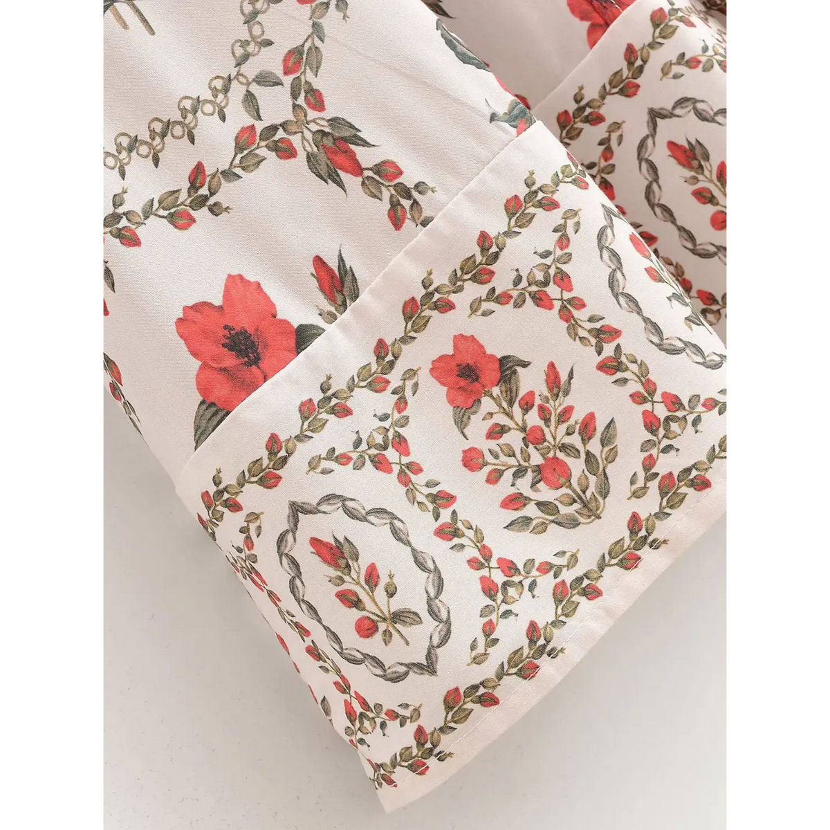 Close-up of sleeve cuff border on floral maxi shirt dress, featuring red botanical flower print and decorative hem trim