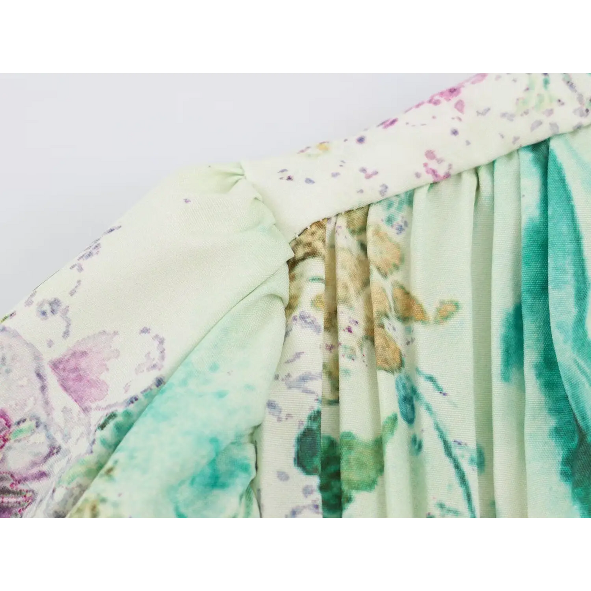 Close-up of watercolor floral print fabric with gathered seams on cream dress
