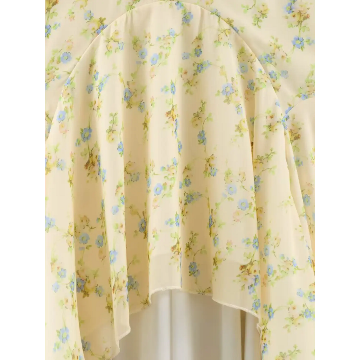 Close-up of the ruffled skirt fabric of floral maxi dress, pale yellow base with blue small floral print, flowy chiffon material