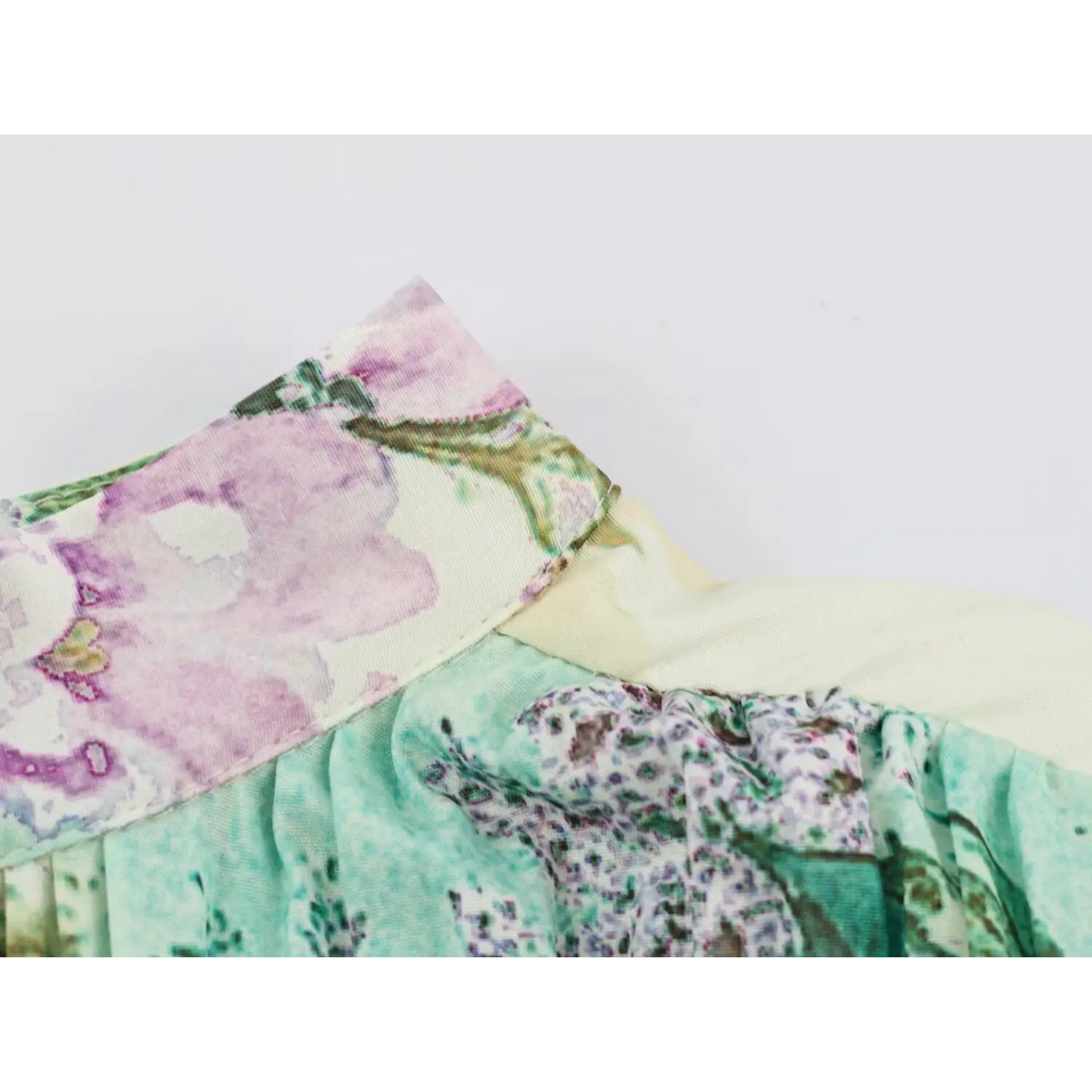 Close-up of fabric panel seam on floral print dress with purple and green flowers
