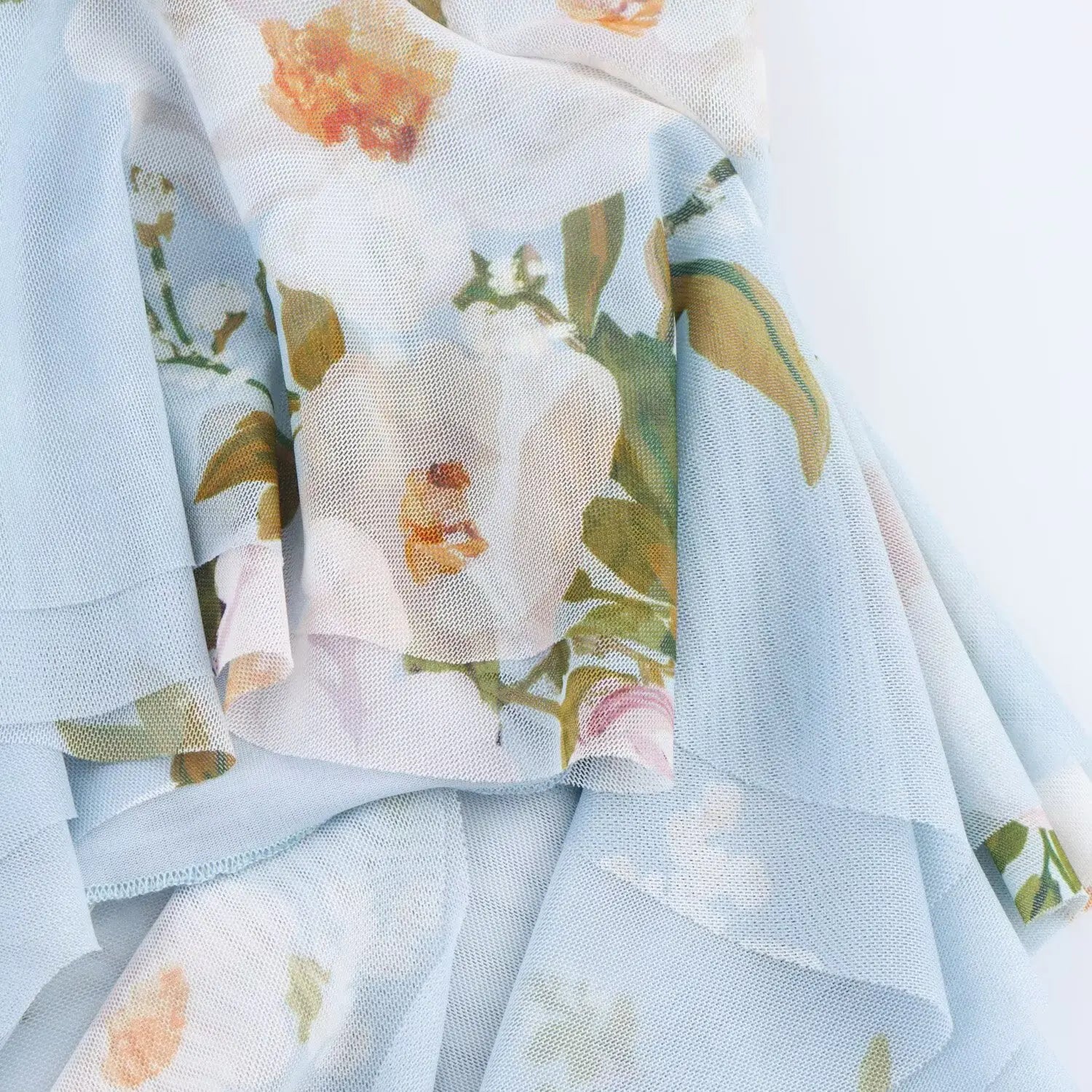 Macro shot of sheer mesh fabric texture with vintage white floral print on light blue base