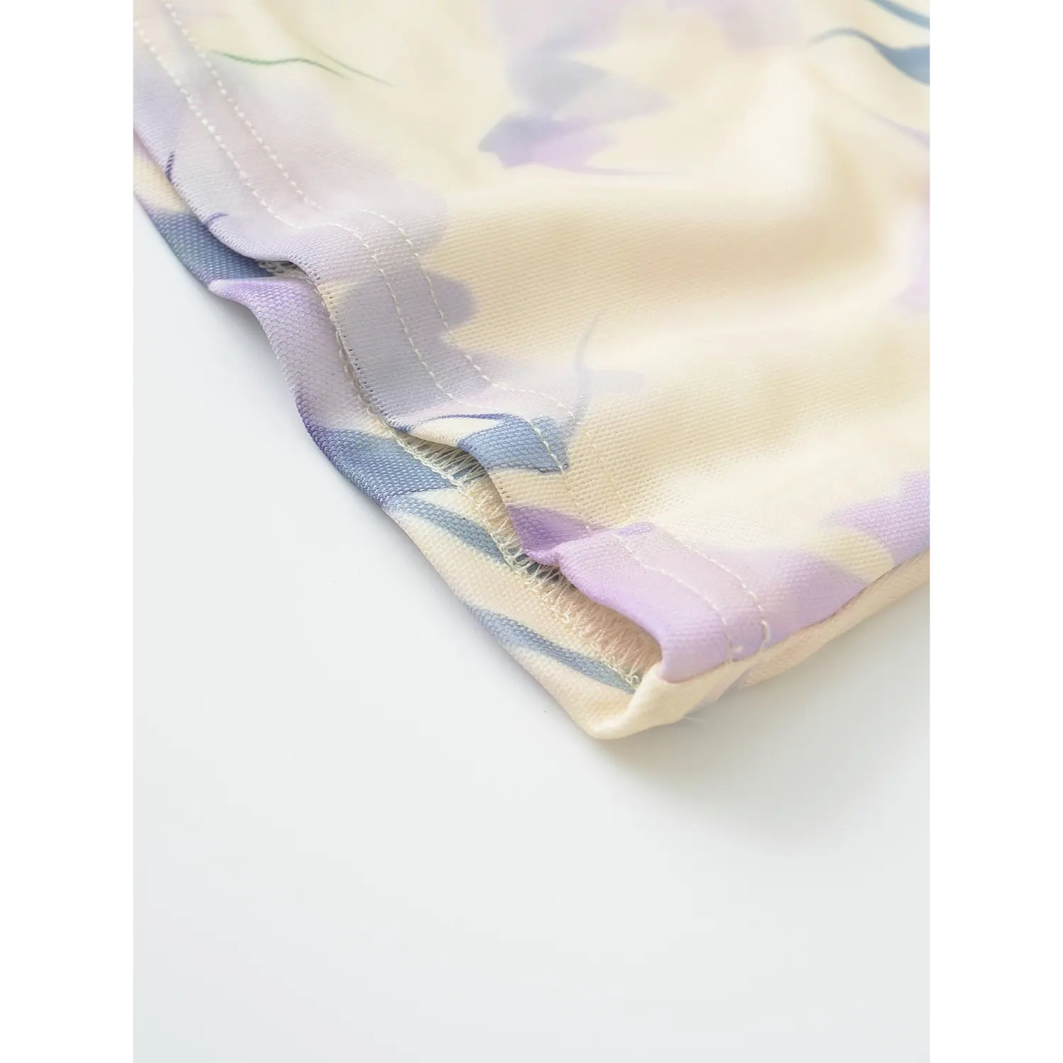 Floral mesh top side seam flat close-up, even straight stitching thin stretch mesh watercolor flower print neat binding fabric white background shot