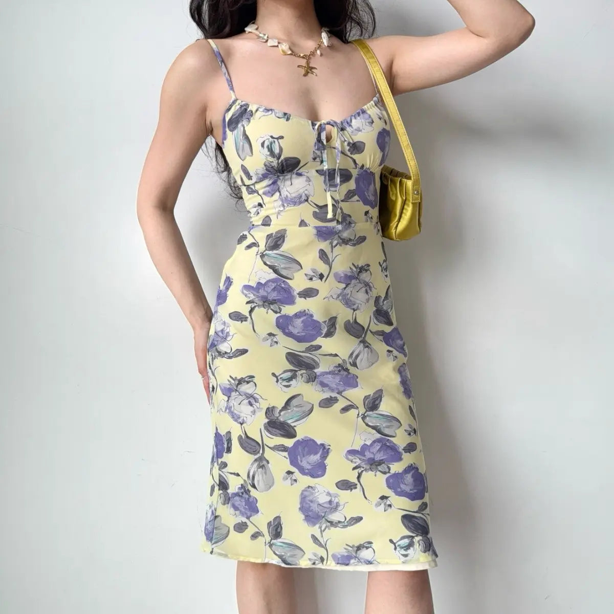The yellow floral midi dress paired with a shell necklace, highlighting the keyhole neckline.
