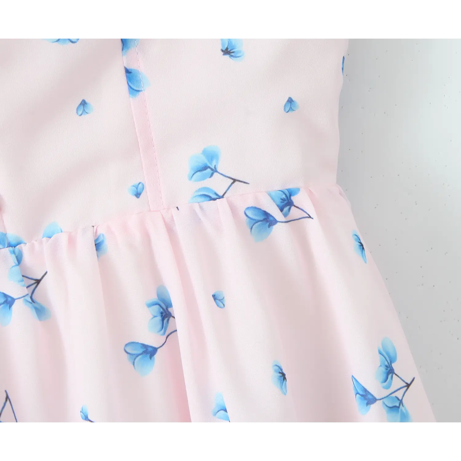 Close‑up waist seam, bodice to skirt gathering, lightweight flowy chiffon, pink background blue flower print
