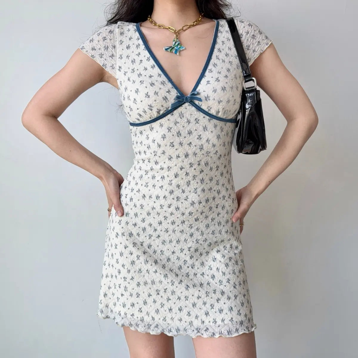 The complete outfit featuring the white floral dress and a black shoulder bag.