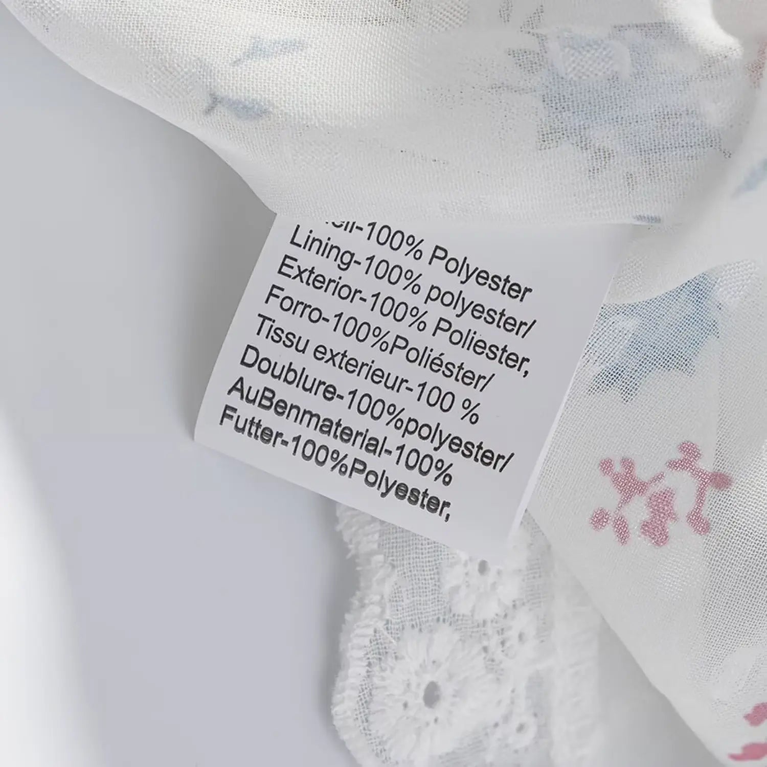 Garment inner care label closeup, multilingual fabric composition text, 100% polyester exterior & lining