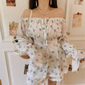 Side standing model view off shoulder floral coord set, elastic ruffle neckline, cinched smocked waist, flowy lace hem shorts, woven straw bag matching vacation style
