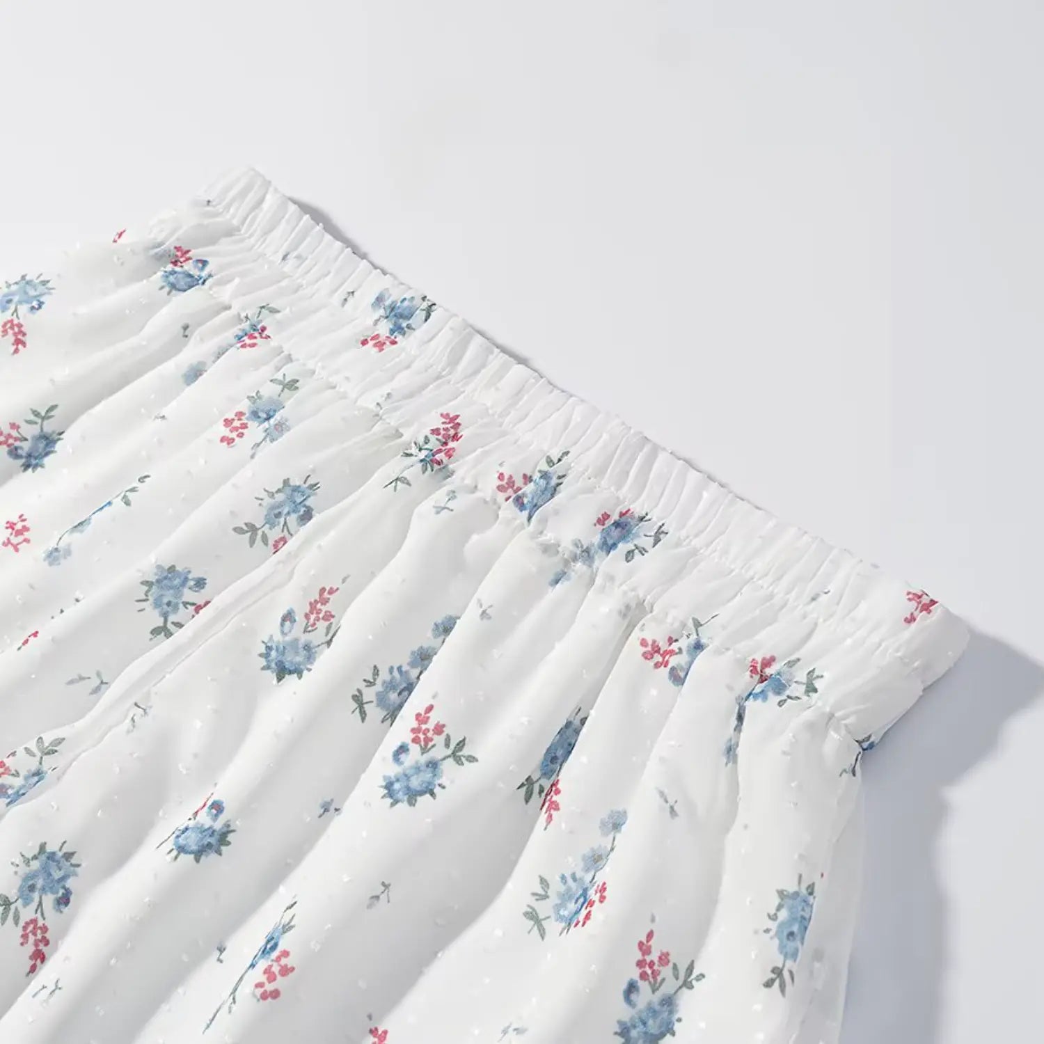 Full waistband overview matching floral shorts, complete stretch elastic waist, evenly spread blue flower print, loose A-line short silhouette