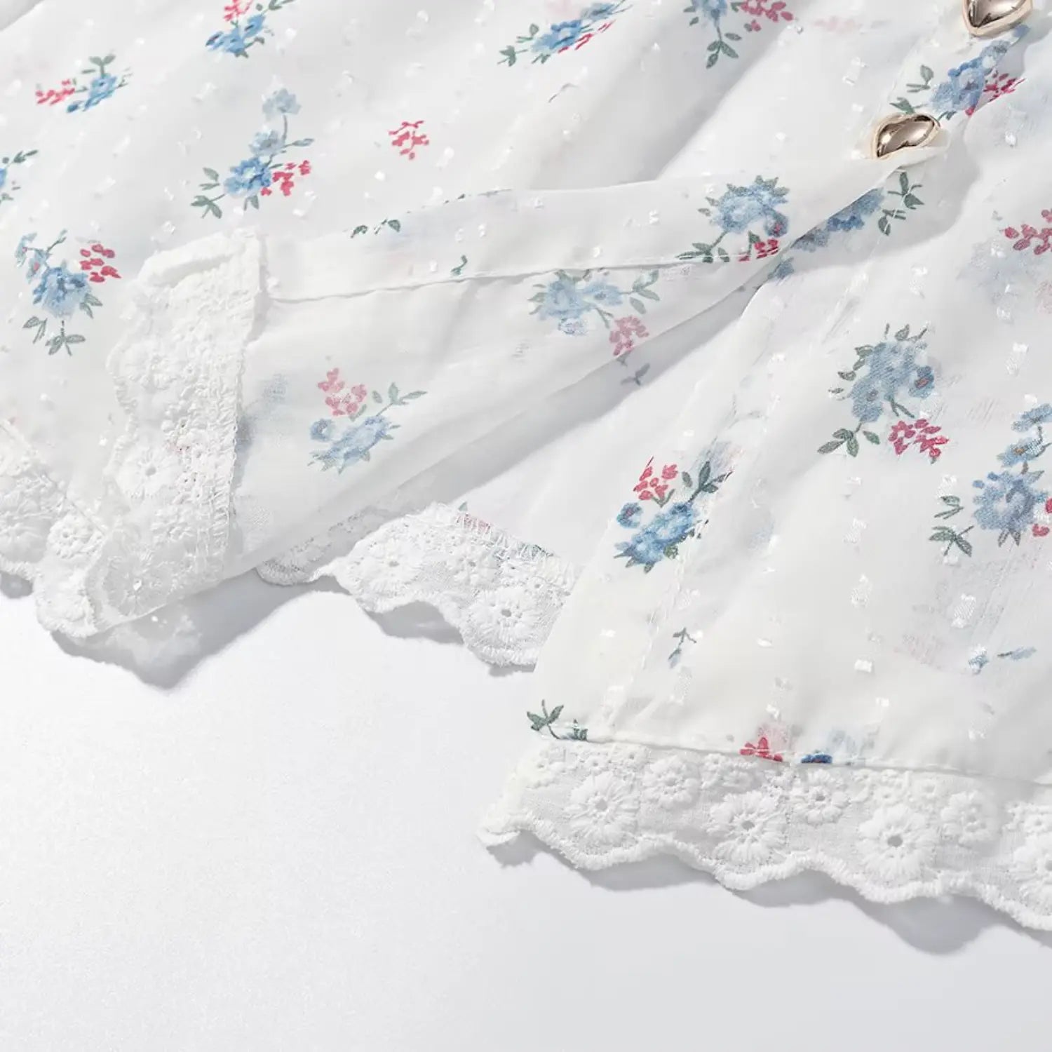 Bottom hem detail of blouse, scalloped eyelet lace trim overlay, layered fabric finish, matching floral print base cloth