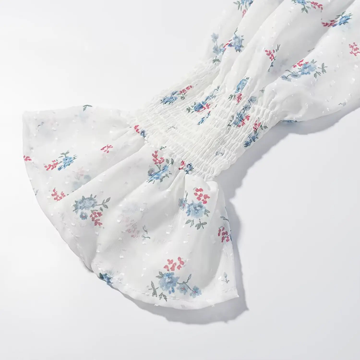 Long flutter sleeve cuff closeup, full horizontal elastic smocked gathering, ruffle flare sleeve edge, sheer floral swiss dot fabric