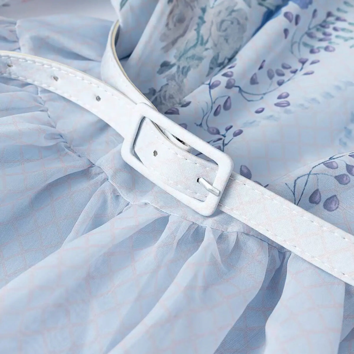 Close-up of white waist belt with square buckle on light blue floral parrot print maxi dress