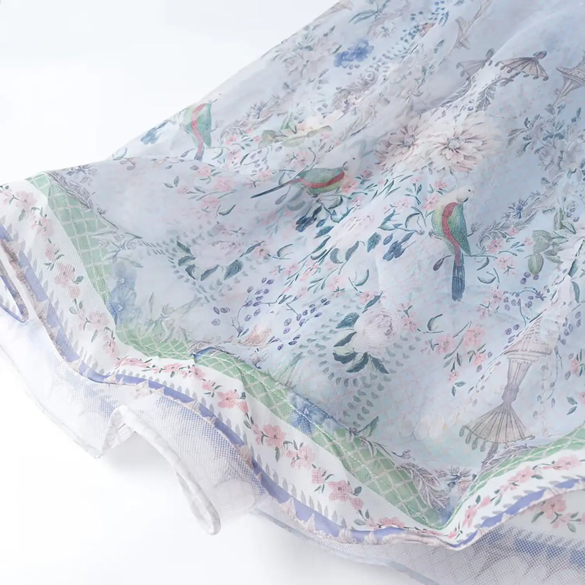 Close-up of maxi dress hem with parrot and floral border print, lightweight sheer chiffon fabric