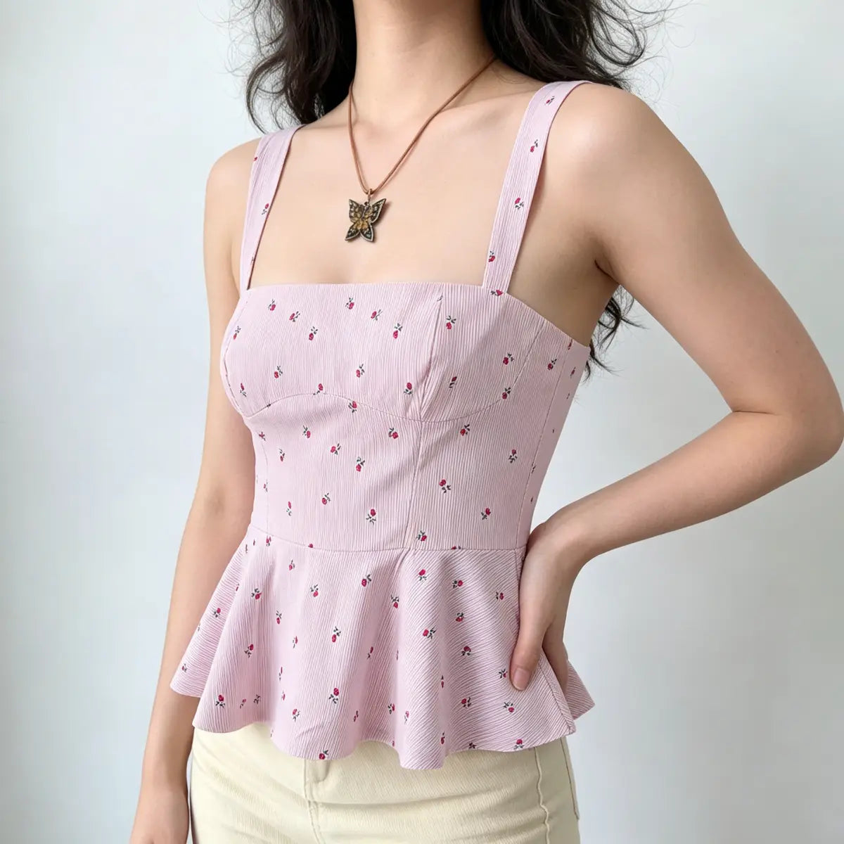 Side view of a light pink floral peplum cami top, showcasing the tailored princess seams, fitted silhouette, and flared peplum hem.