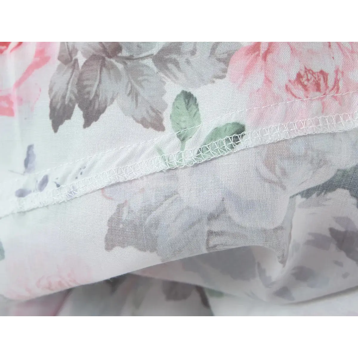 Close-up of the hem and stitching on a pink and green floral print dress.
