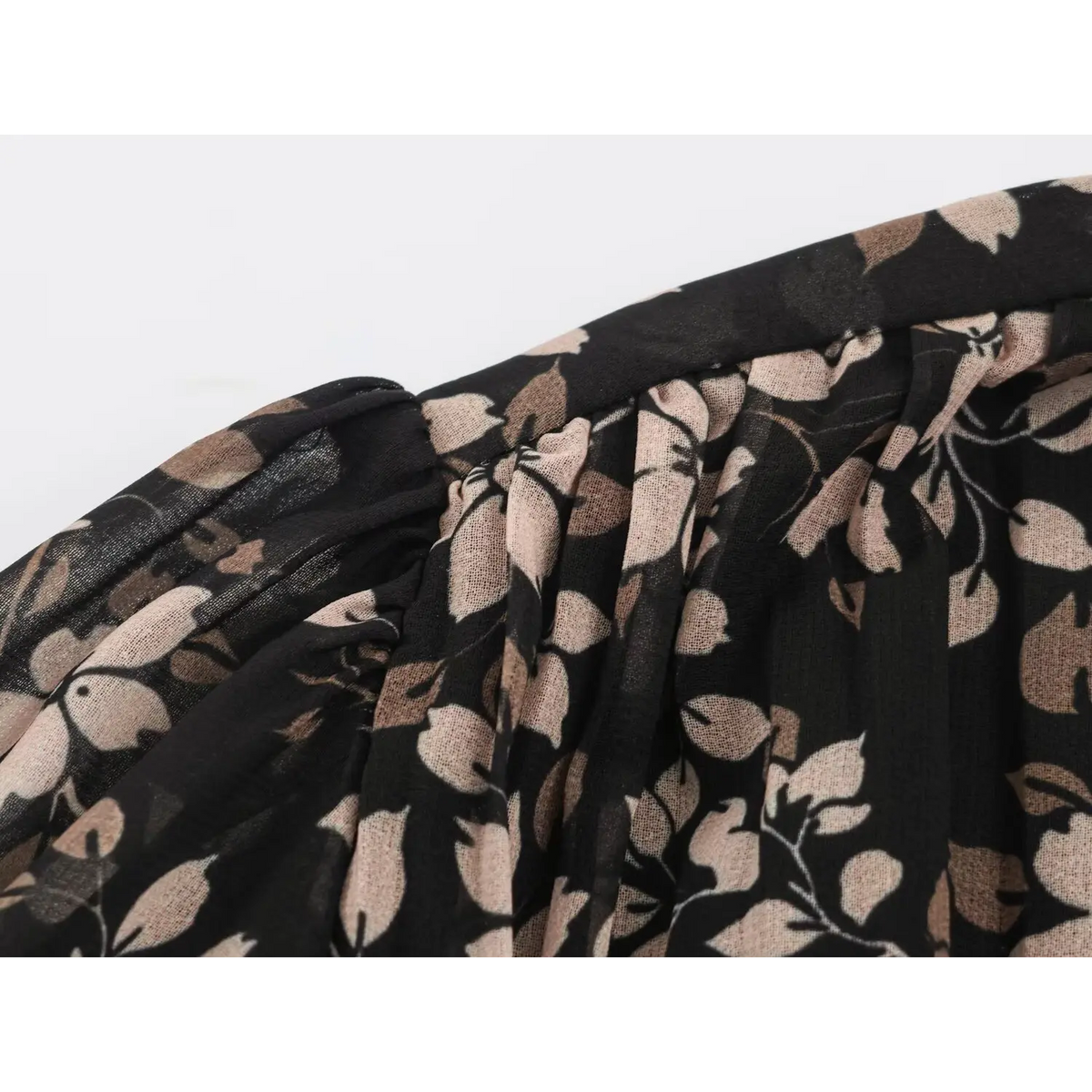 Close-up of black fabric with khaki leaf print and gathered pleat details