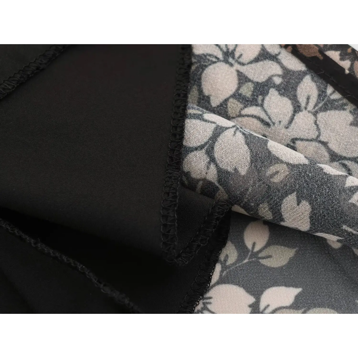 Close-up of black fabric seam with neat binding joined with floral printed fabric