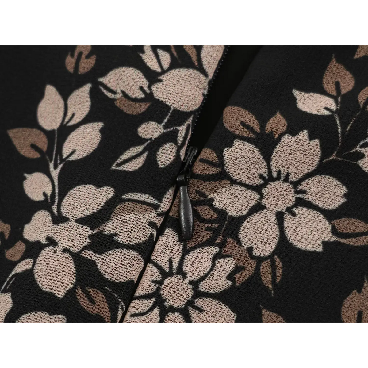 Close-up of black zipper on floral printed fabric with cream and brown flowers