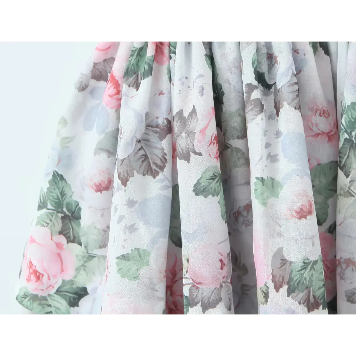 Close-up of the pink rose and green leaf print fabric on a tiered dress skirt.