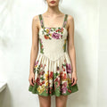 Model wearing floral print spaghetti strap mini dress, square neckline, fitted waist, flared skirt with fruit and botanical pattern