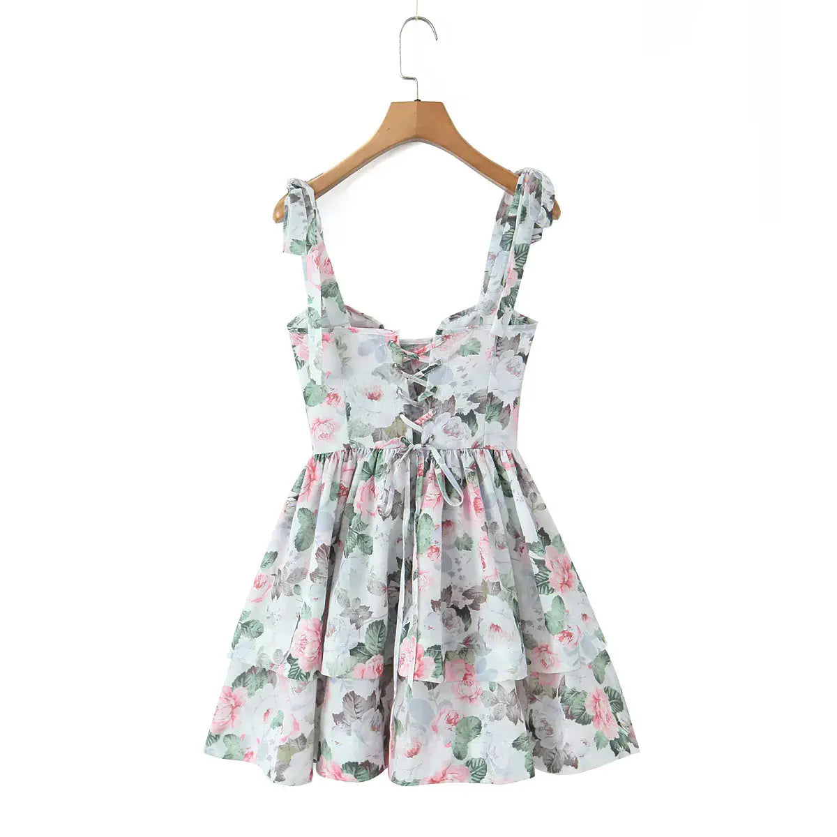 Back view of a floral print corset dress hanging on a wooden hanger, showing the lace-up tie closure.