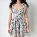 Full-body shot of a woman wearing a floral print corset mini dress with tie straps, sweetheart neckline, and tiered skirt.