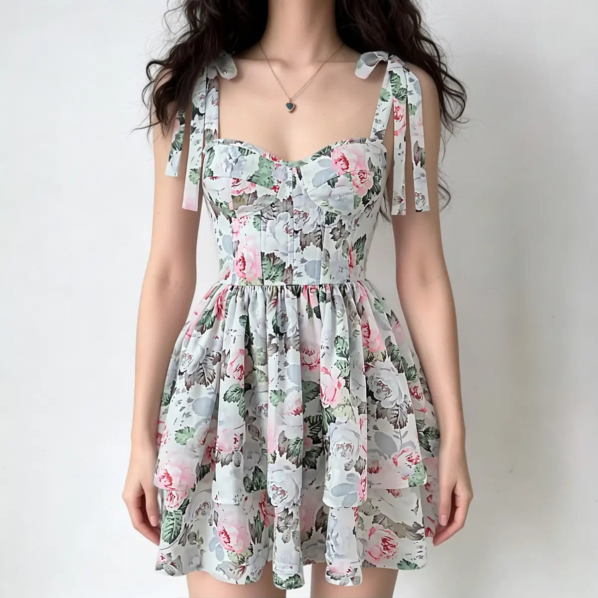 Full-body shot of a woman wearing a floral print corset mini dress with tie straps, sweetheart neckline, and tiered skirt.