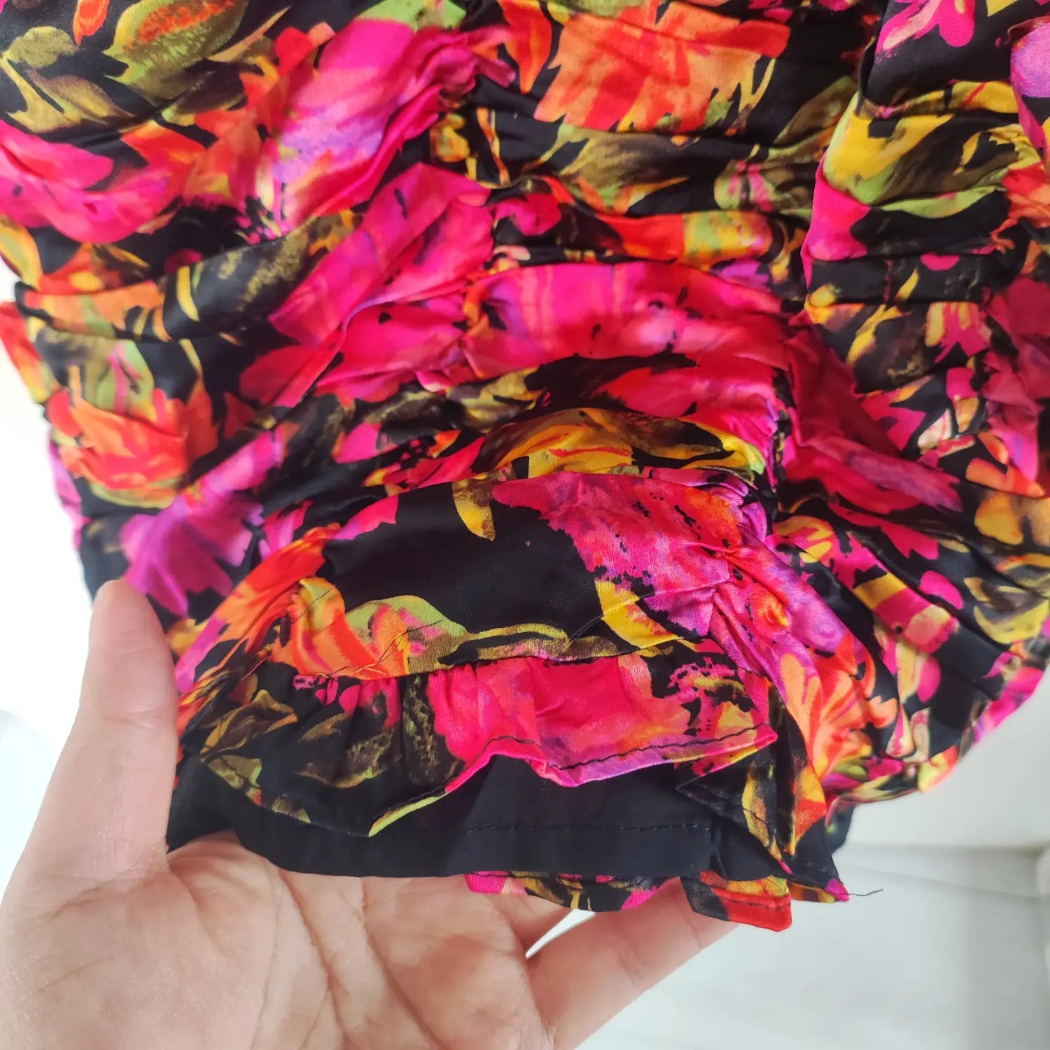 Close‑up bottom hem ruffle and inner lining seam detail bright floral ruched mini dress