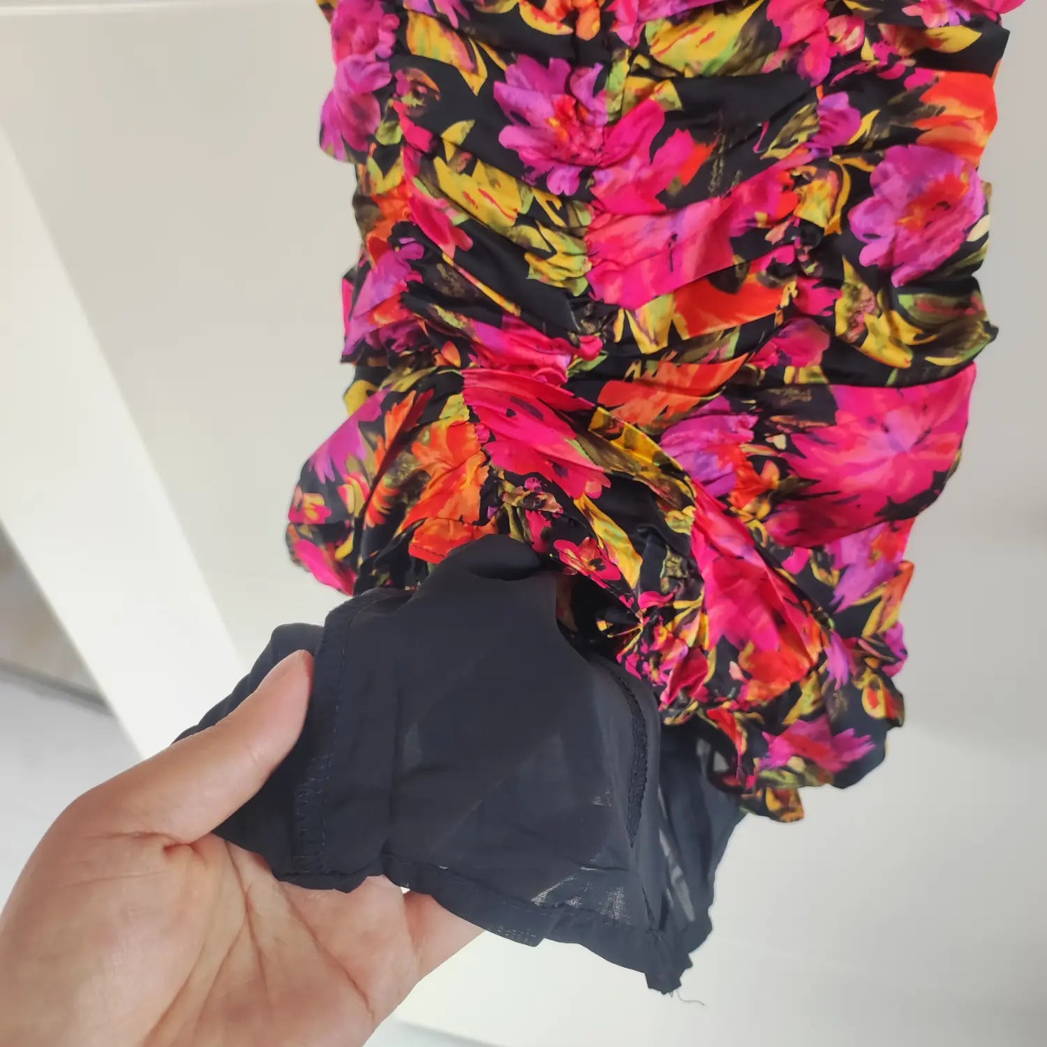 Close‑up inner black lining fabric and hem construction bright floral ruched cami mini dress