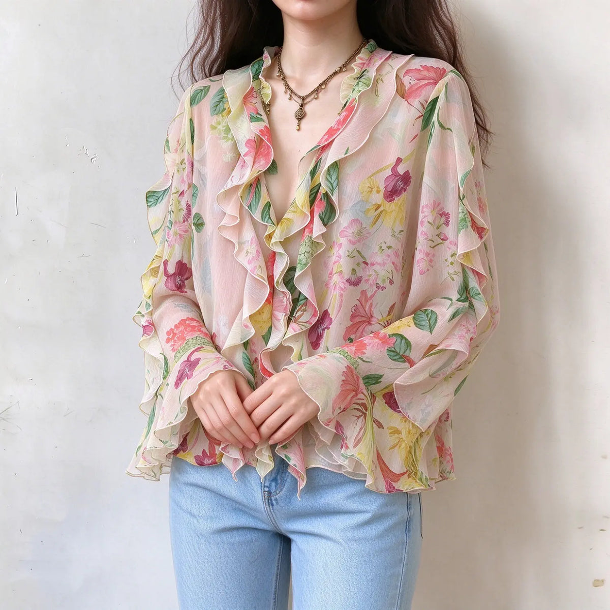 Female model wearing sheer floral ruffle blouse, hands crossed in front, show full ruffle details on neckline and sleeves