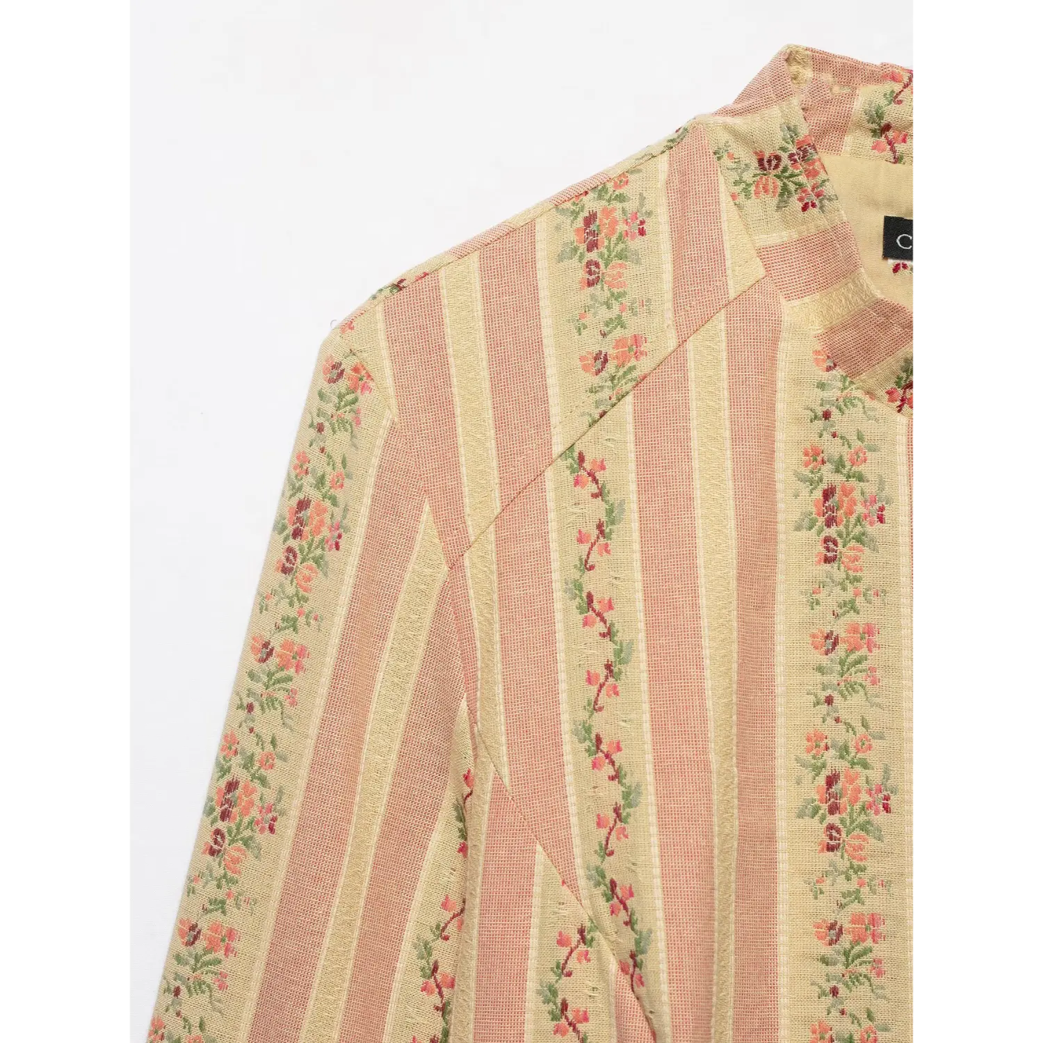 Close up texture of pink floral stripe woven fabric, shoulder raglan seam and small flower vine print detail