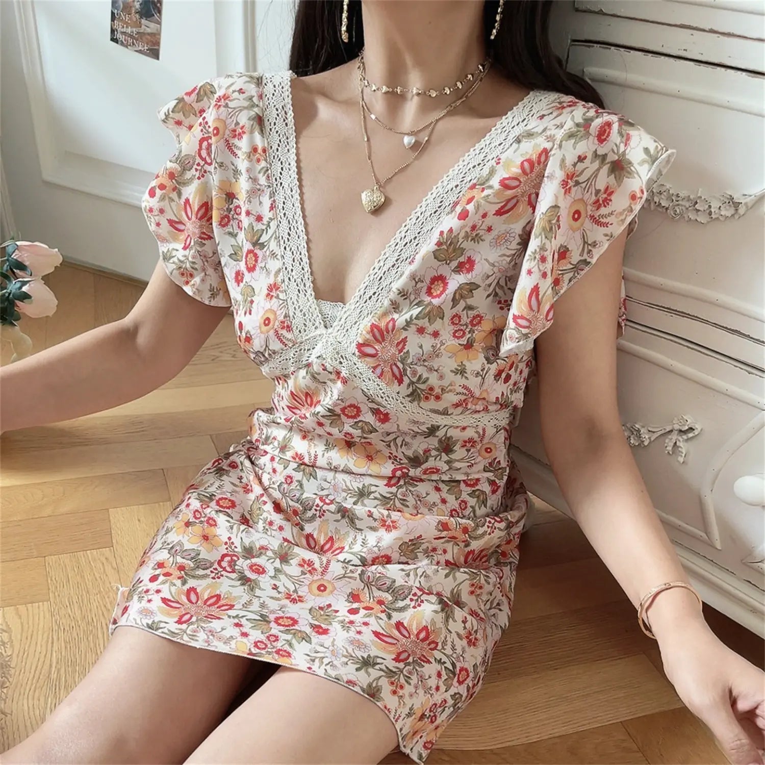 Side sitting lifestyle view lace V neck floral mini dress, waist ruched slim silhouette, soft ruffle cap sleeve cottagecore short dress