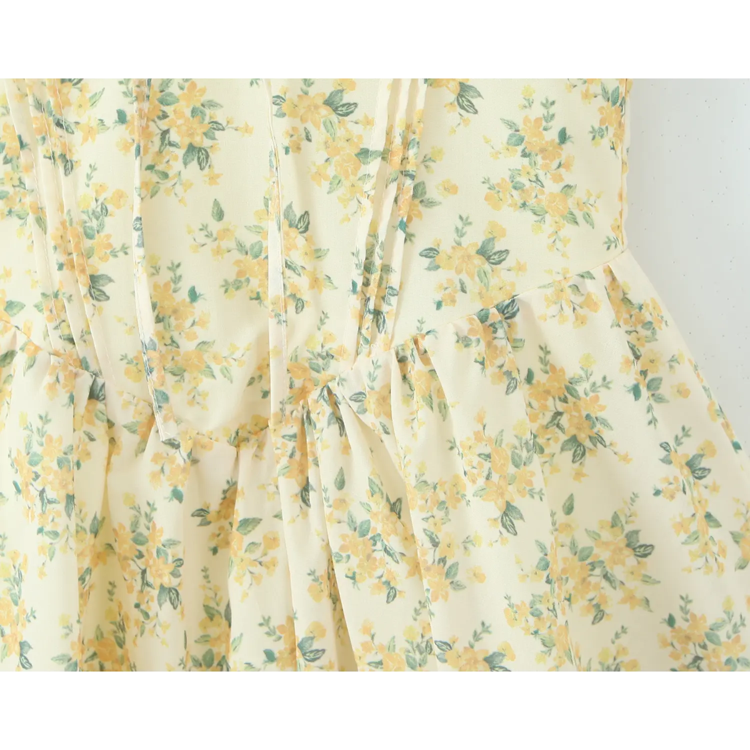 Close‑up of corset ruched waist seam on yellow floral halter mini dress