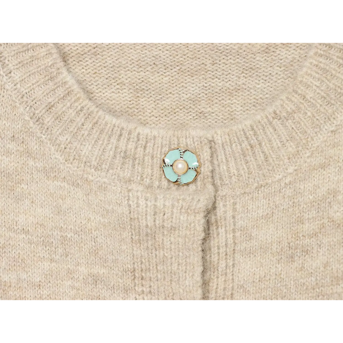 Macro closeup of mint green floral button with pearl center on oatmeal knit cardigan