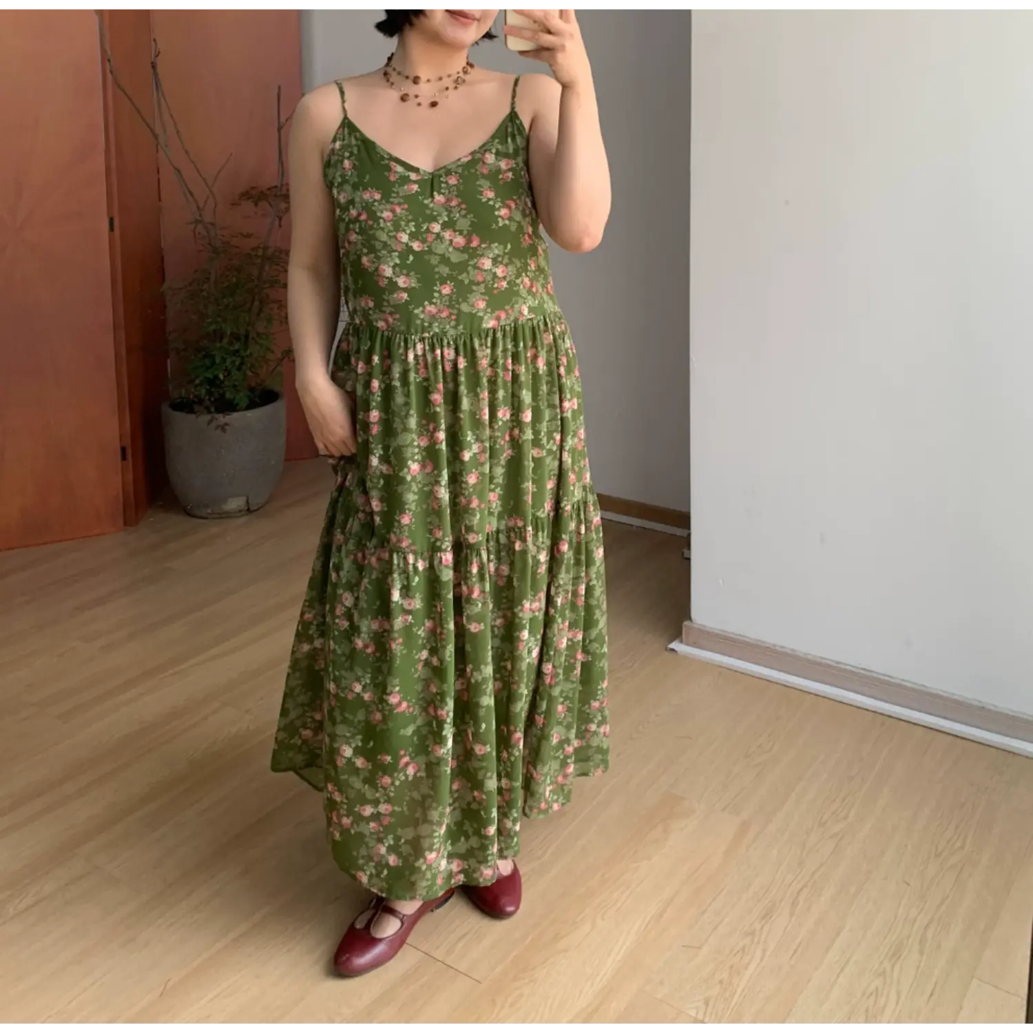 Straight full front indoor mirror shot of dark green micro pink floral tier maxi slip dress, loose flowy A-line layered skirt, matching burgundy leather mary jane flats