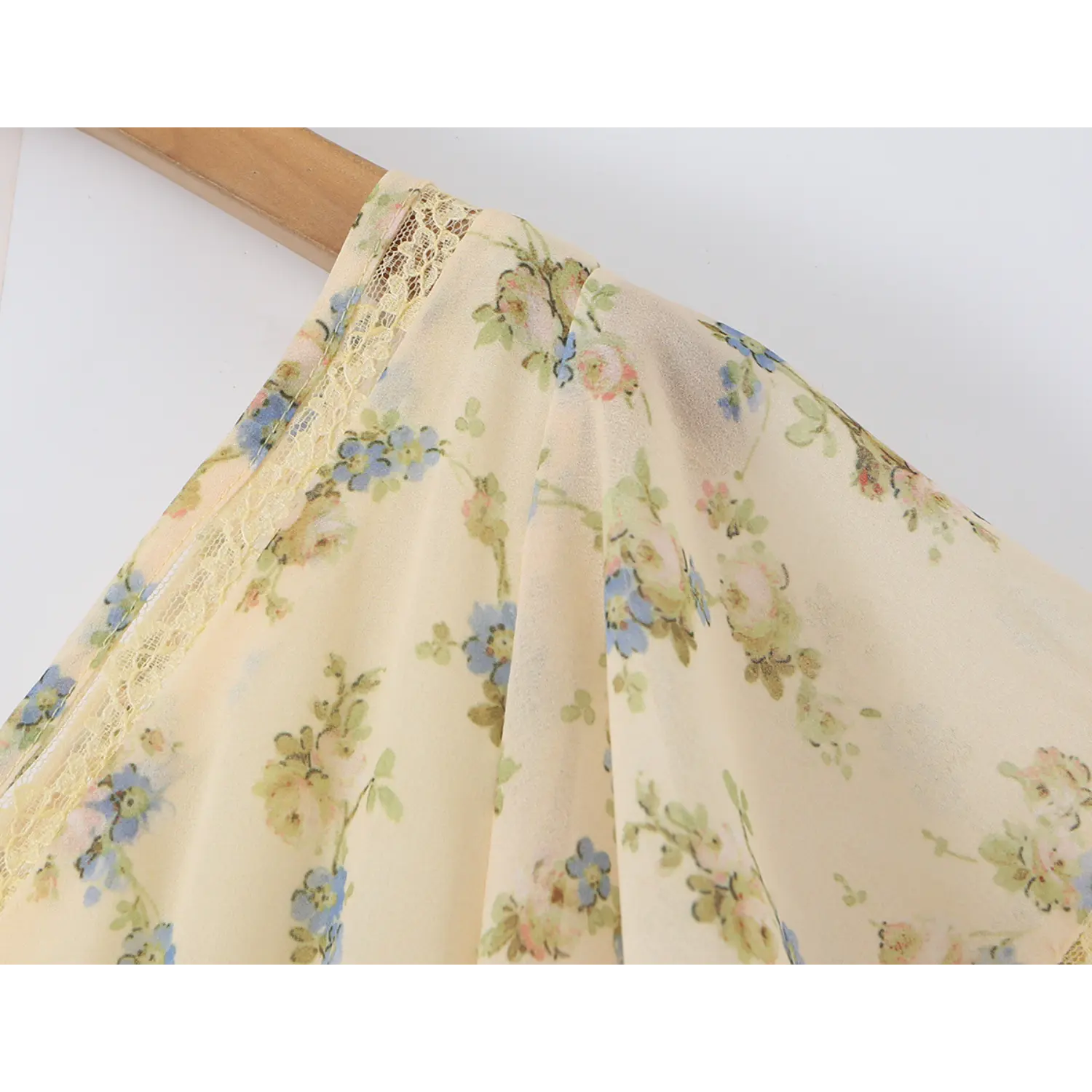Partial shot of flutter short sleeve edged with yellow lace, semi-sheer cream chiffon fabric printed with blue and pink wild floral patterns