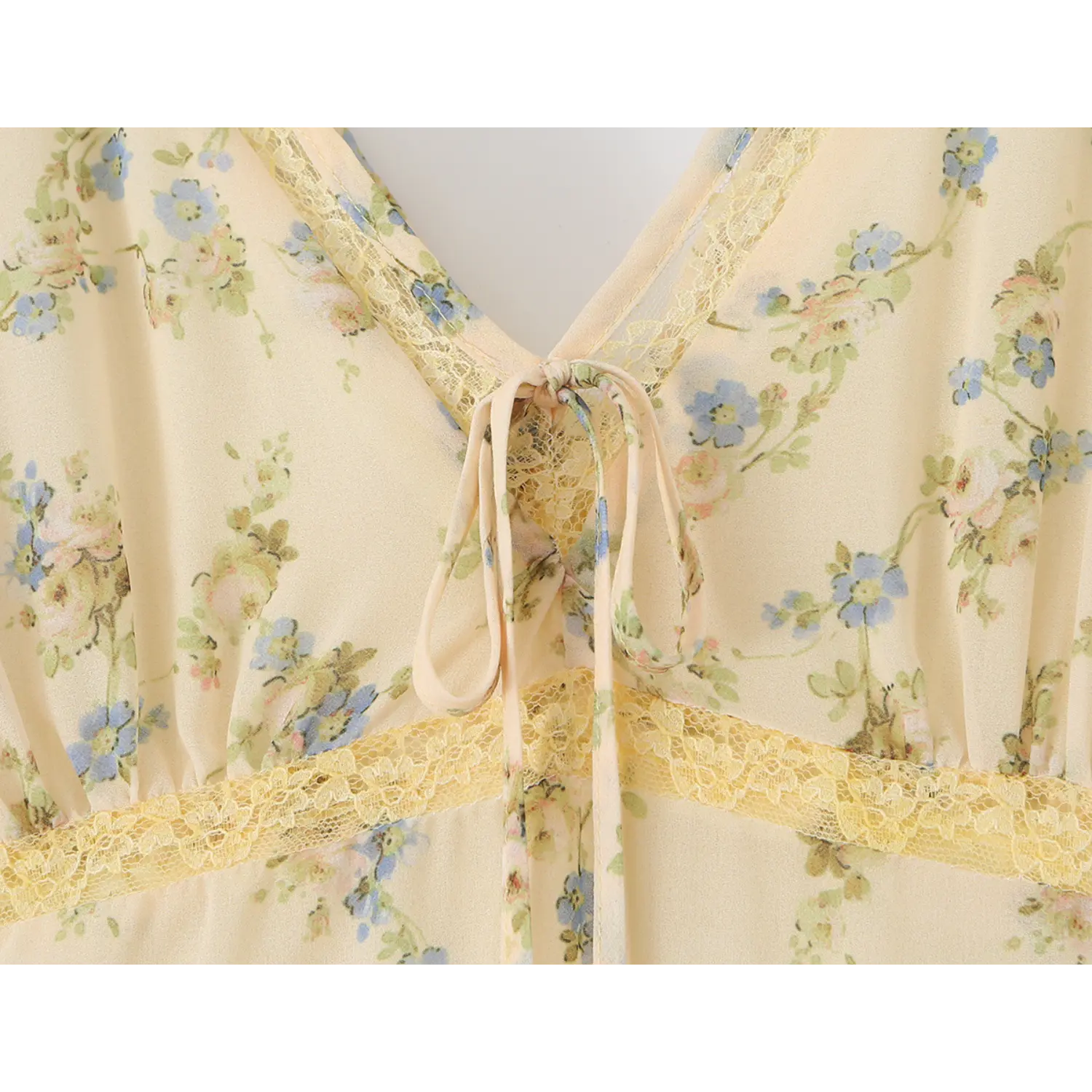 Macro close-up of fabric self tie and yellow lace v-neck trim, vintage blue small floral print on lightweight cream chiffon garment