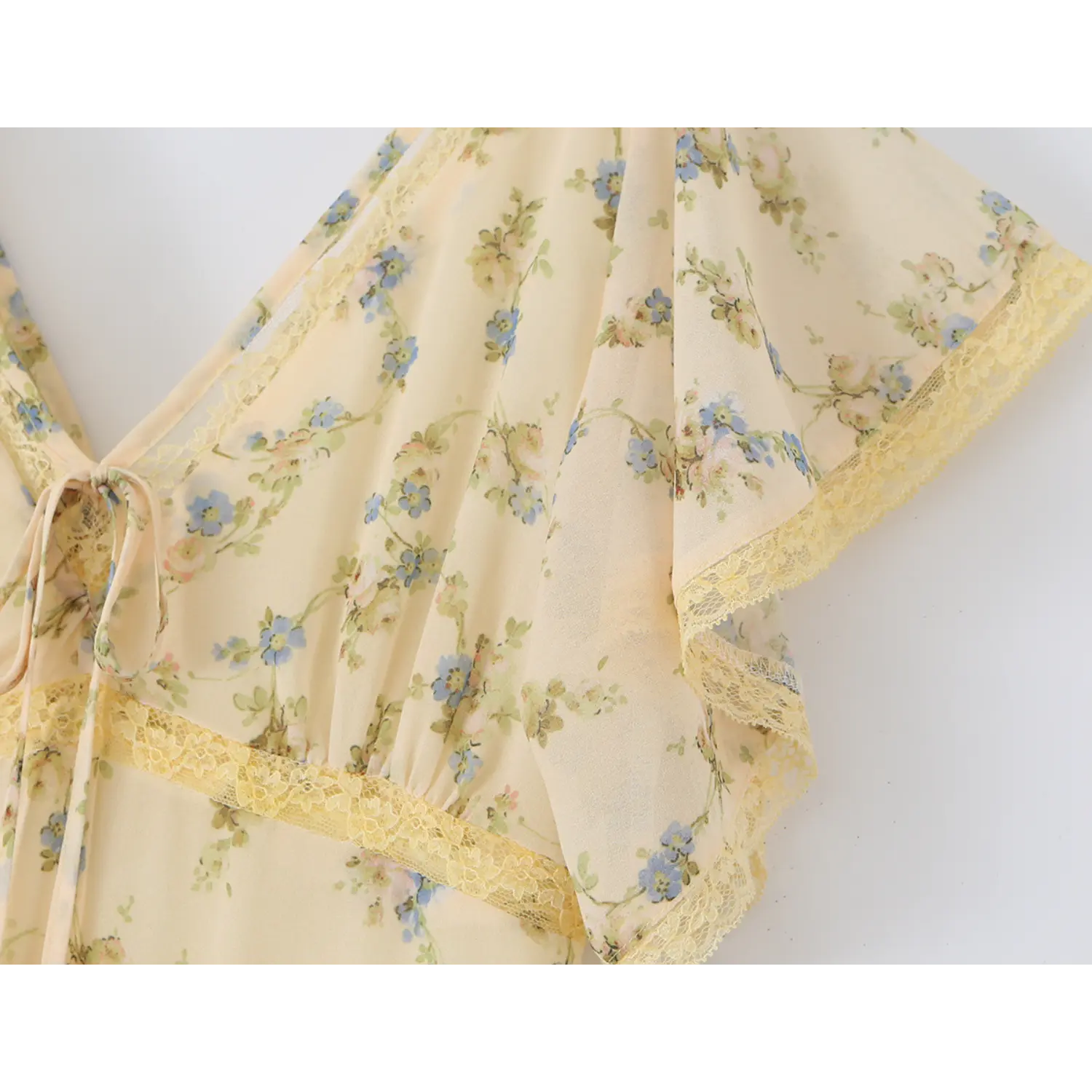 Close-up shot of v-neck tie bust with yellow lace trim, sheer cream chiffon printed with small blue wildflowers for women vacation long gown