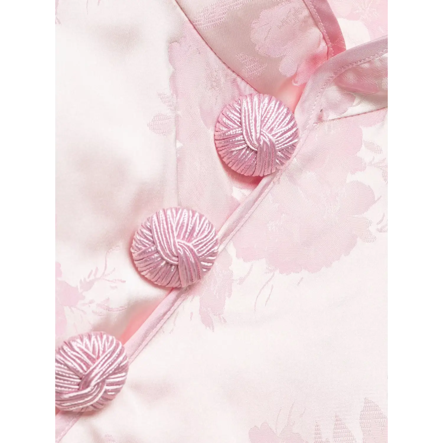 Diagonal frog buttons macro close-up, wrapped pink fabric knot detail, jacquard floral background