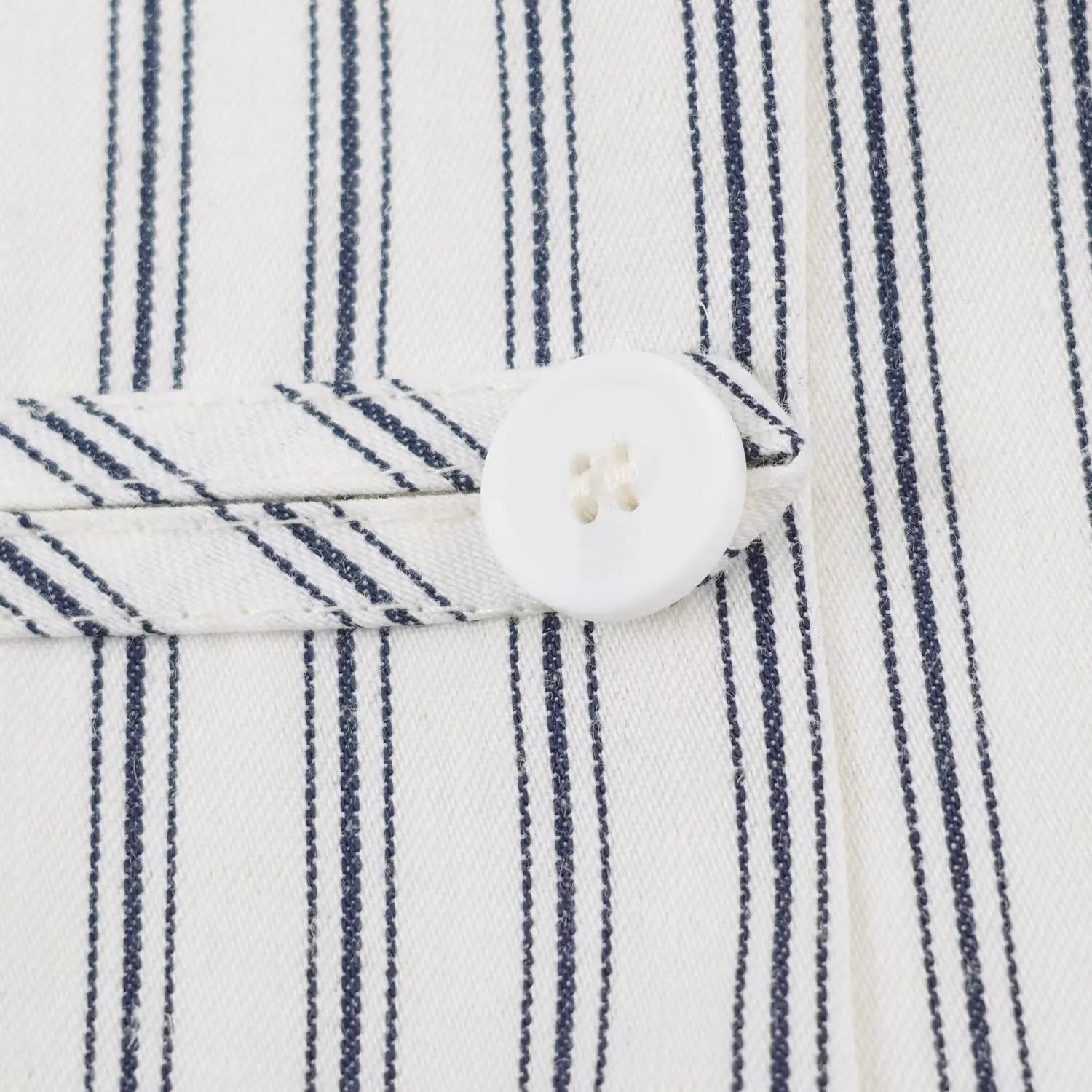 Front decorative placket macro shot, matching fabric strip + round white plastic buttons, vertical stripe textured fabric
